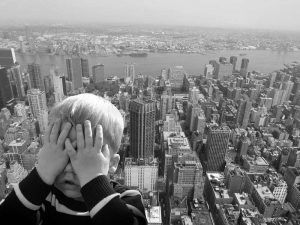 Child with hands over face looking over cityscape