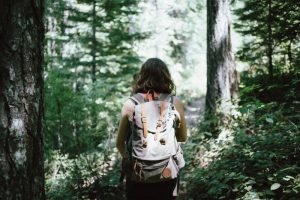 Woman walking through a forest with a gray backpack on